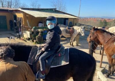 Niño con casco montado a caballo junto a la cuadra antes de la ruta a caballo en Gijón